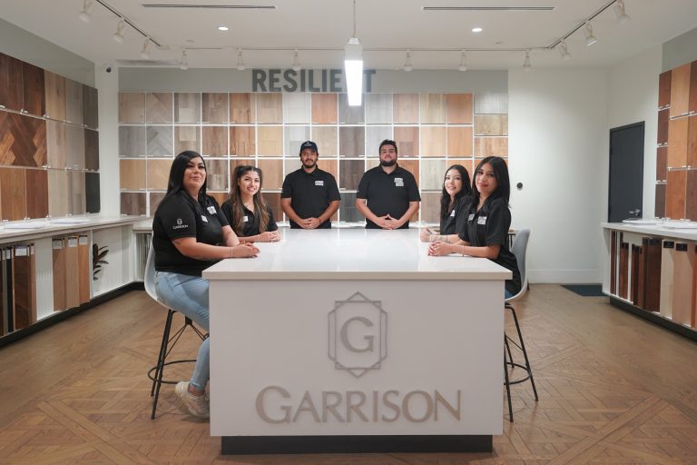 The Garrison sales team at the Van Nuys showroom with flooring samples on the walls