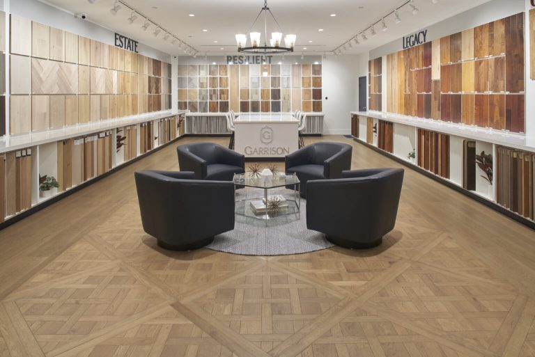 The Garrison Van Nuys showroom with flooring samples on the walls and a beautiful custom wooden floor with leather chairs and a glass table